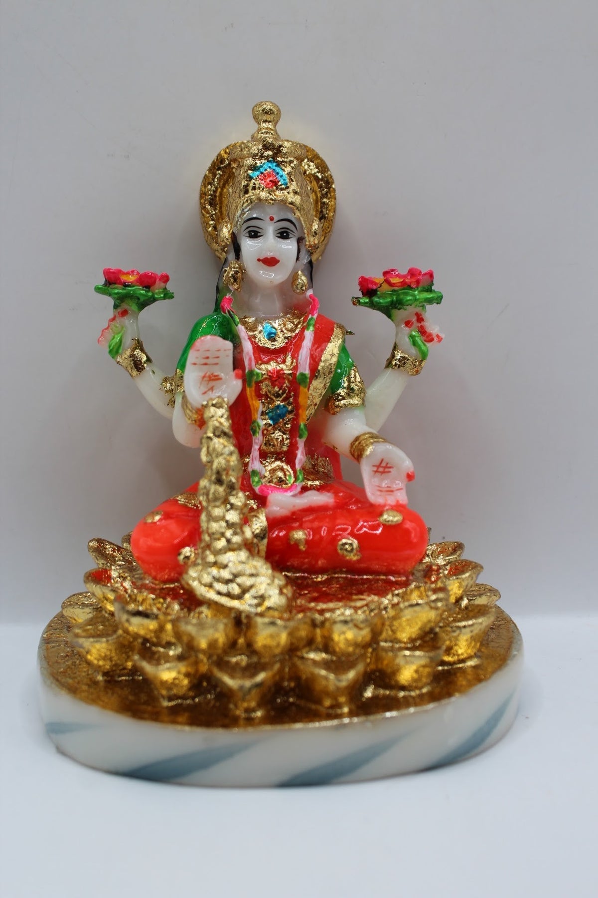 Resin Laxmi murti seated on gold coins, white base, front view