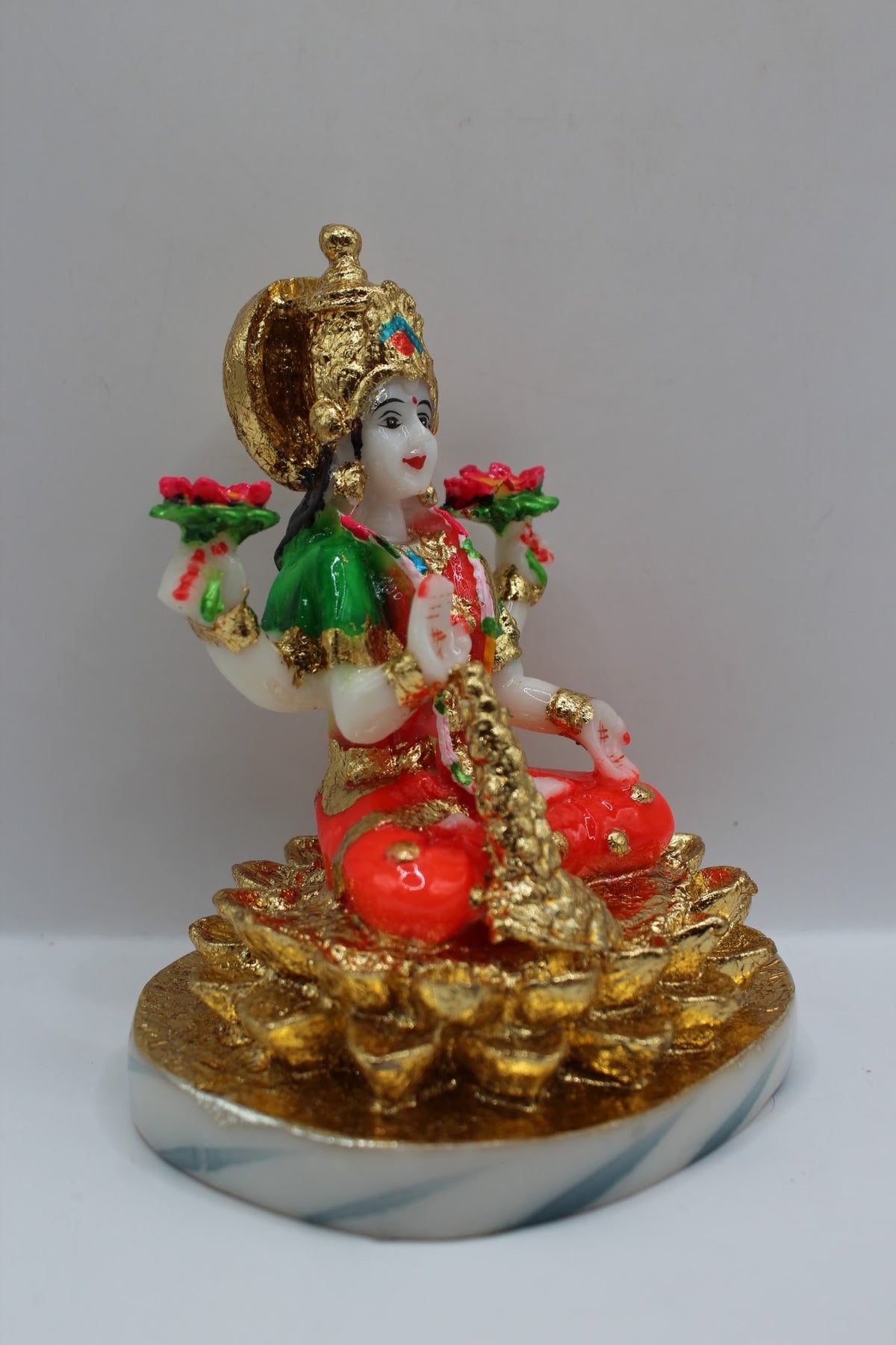 Resin Laxmi murti seated on gold coins, white base, left side view