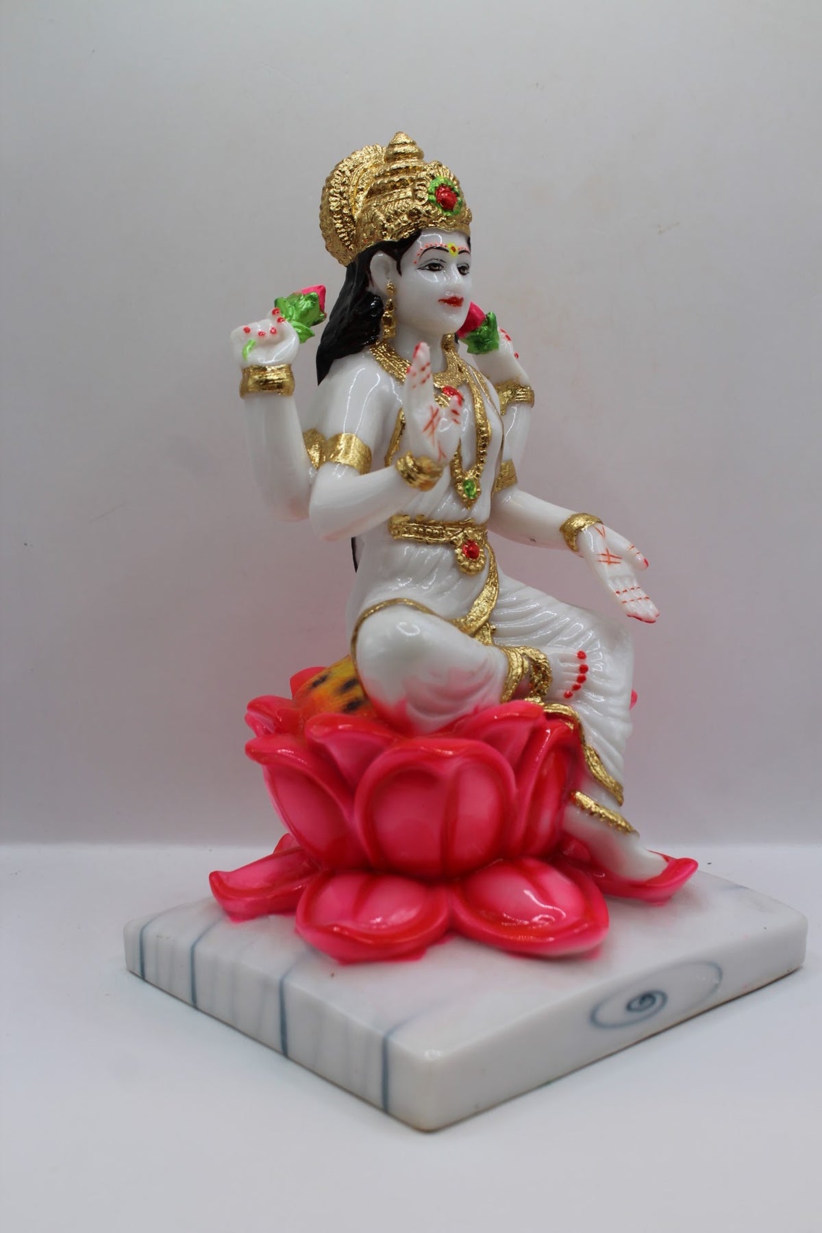 White and gold resin Laxmi murti on a pink lotus, left side view