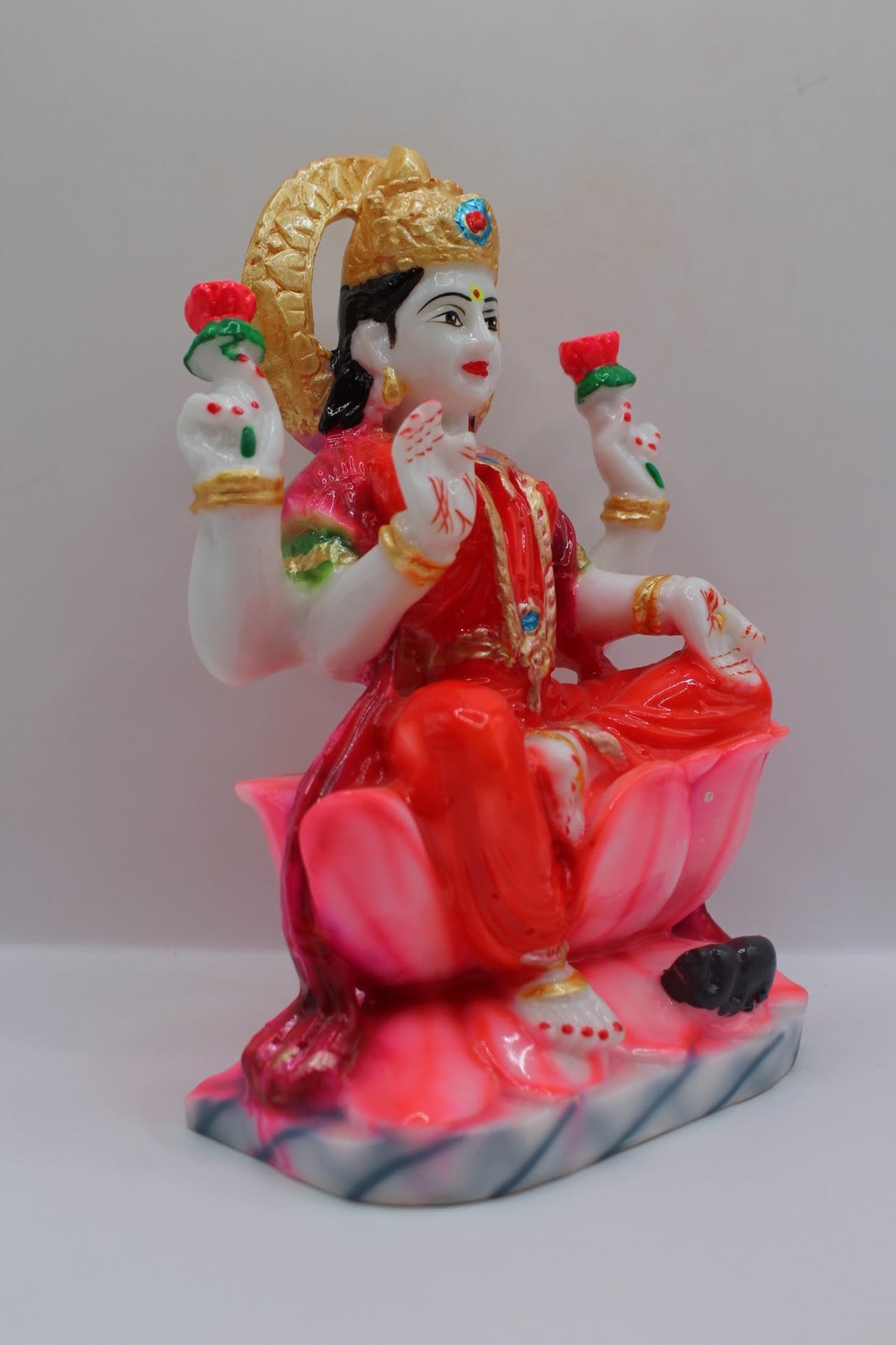 Red resin Laxmi murti on a pink lotus, left side view