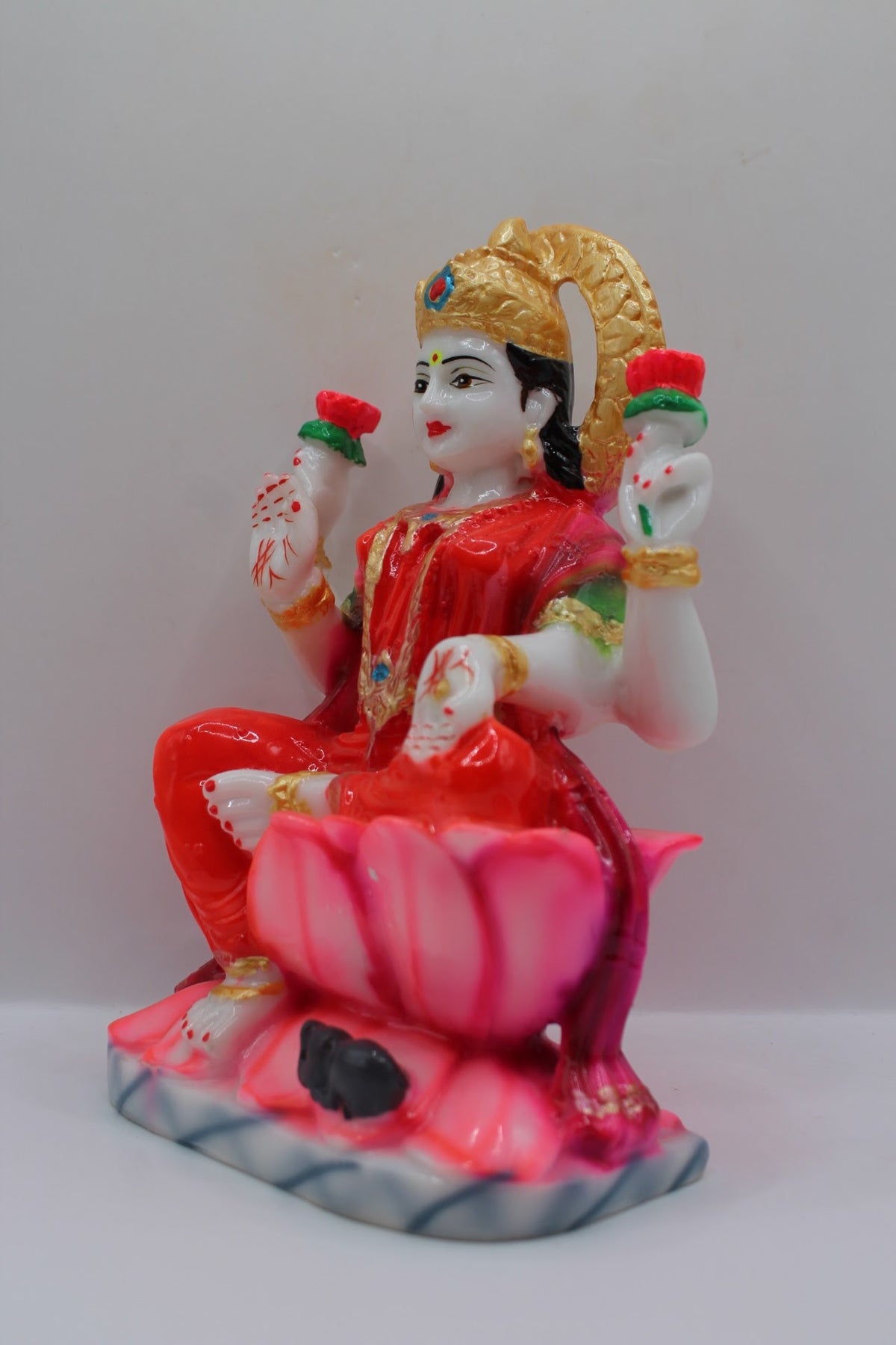 Red resin Laxmi murti on a pink lotus, right side view