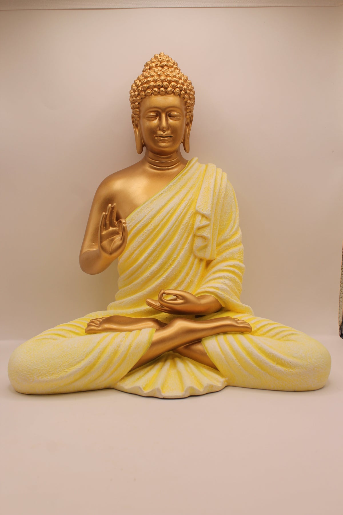 Resin Buddha statue with pastel yellow robe and gold skin, front