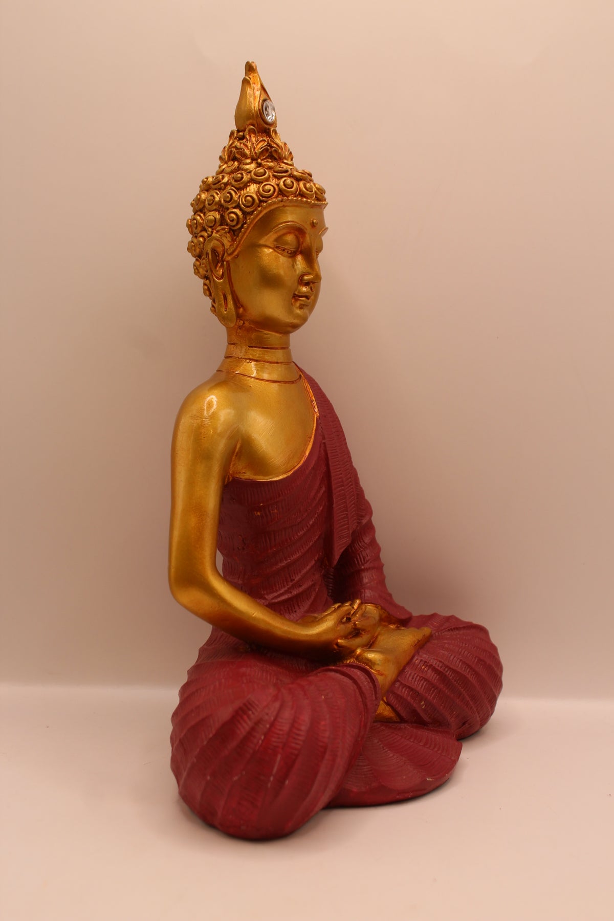 Maroon meditating Buddha statue, left side