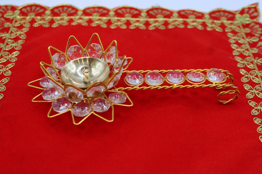 Gold-tone lotus aarti diya set with faceted pink stones and a jewelled handle