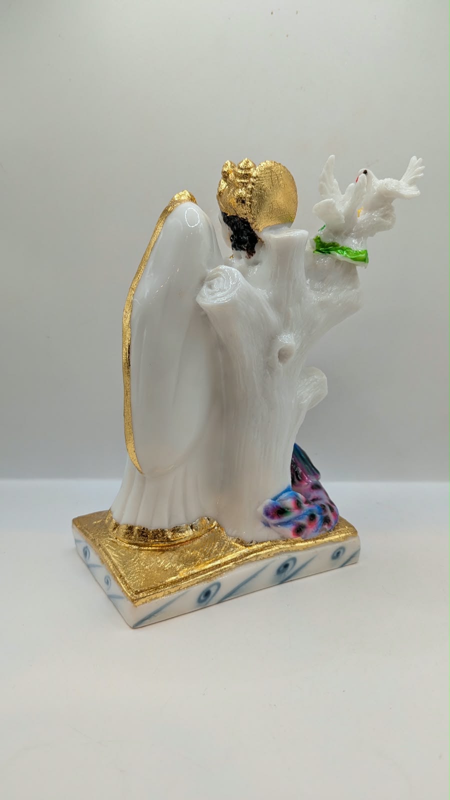 White and gold Radha Krishna statue with peacock, back view