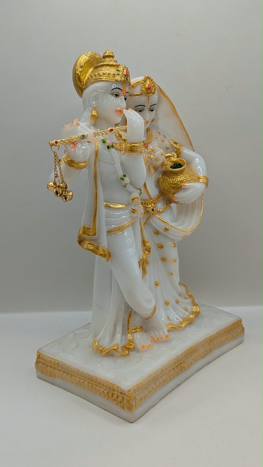 White and gold Radha Krishna statue with flute, side view