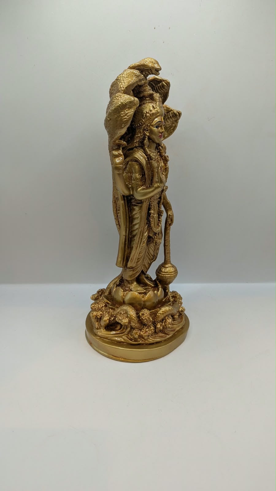 Gold Lord Vishnu statue with snake hood, side view