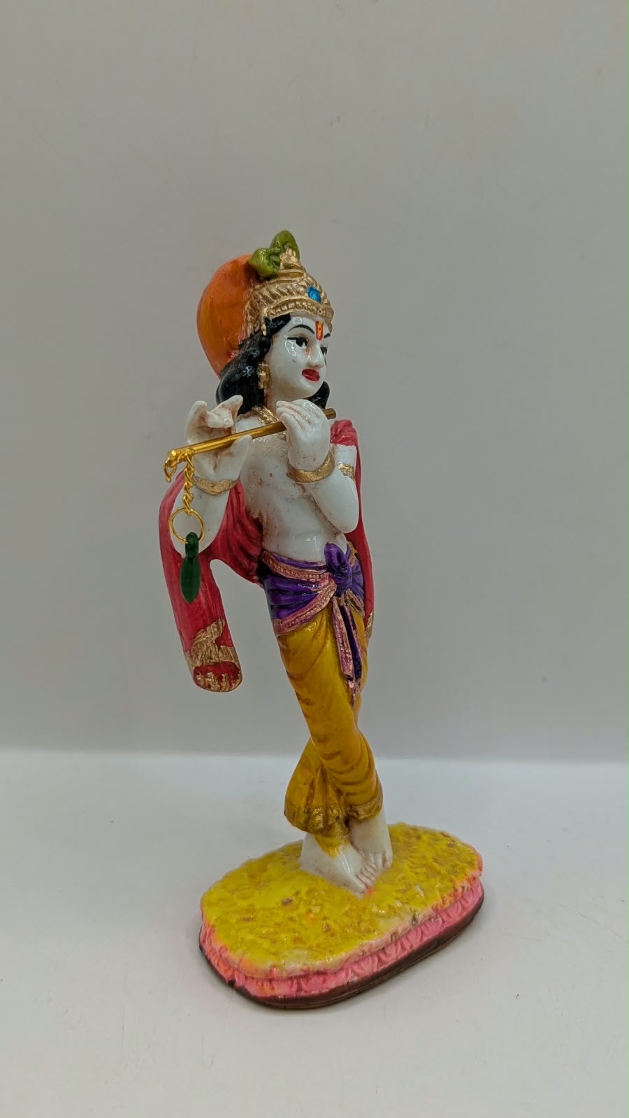 Colourful Lord Krishna statue with flute, side view