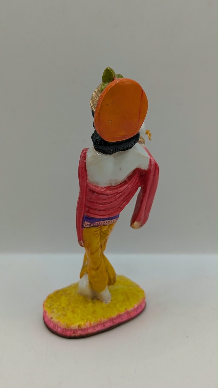 Colourful Lord Krishna statue with flute, back view