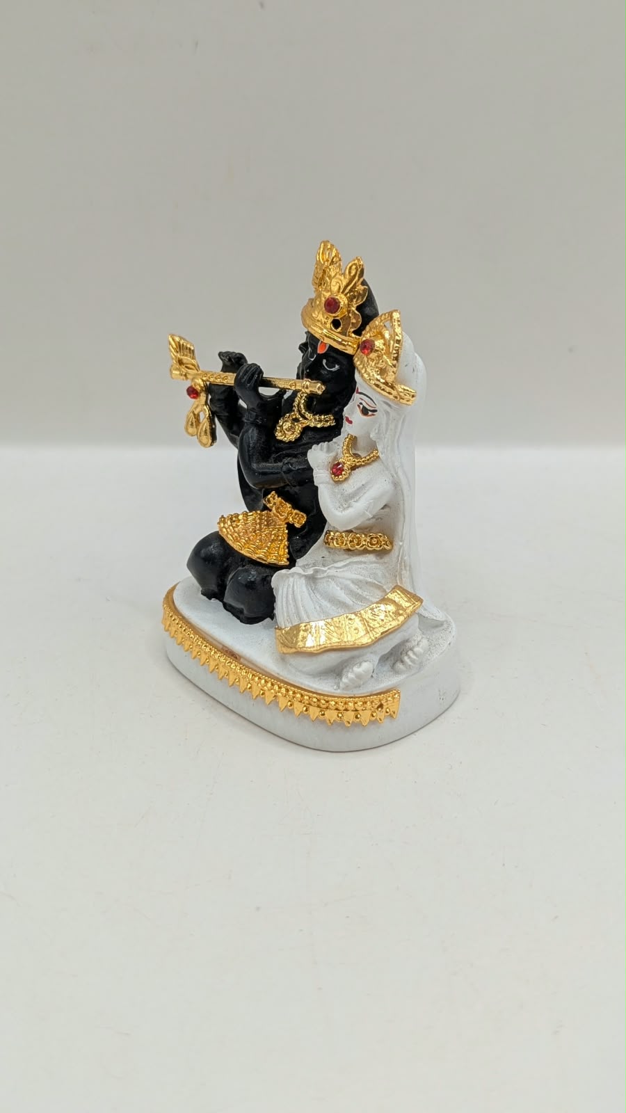 Black and white Radha Krishna statue with gold, other side view