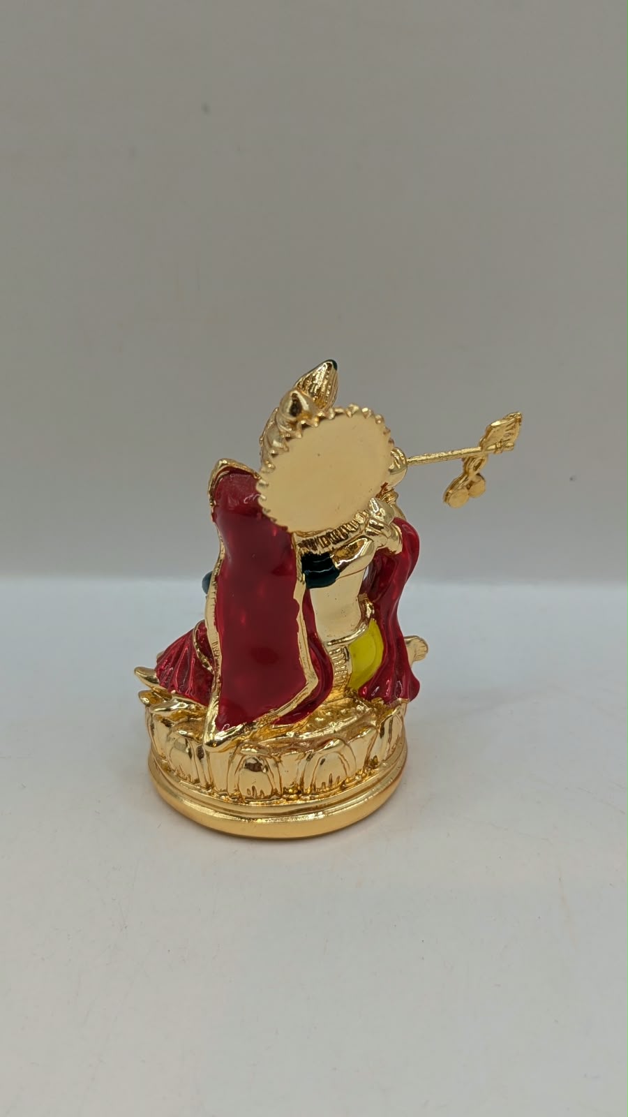 Gold Radha Krishna statue on a lotus base, back view