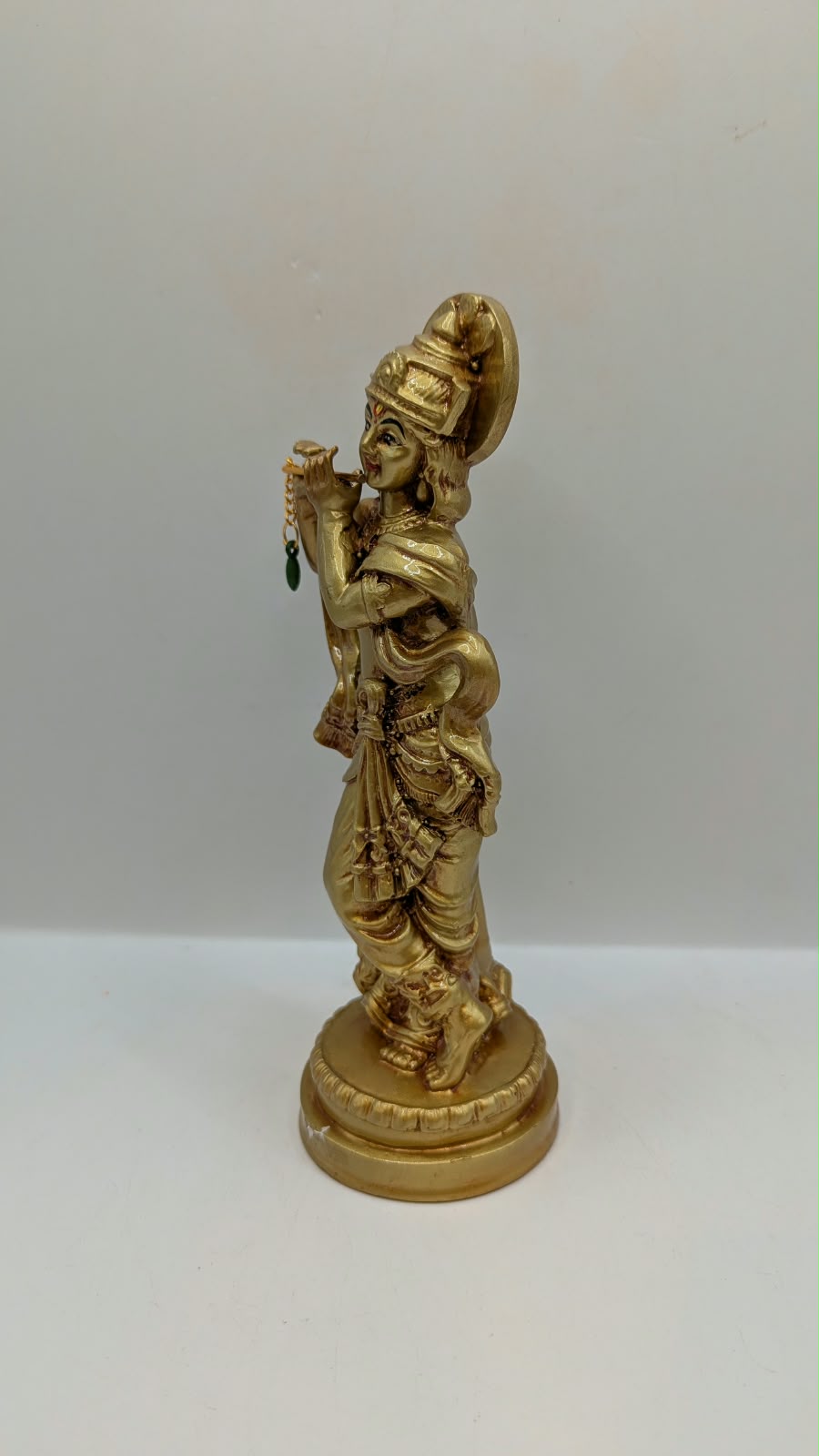 Gold Krishna statue with flute and halo, other side view