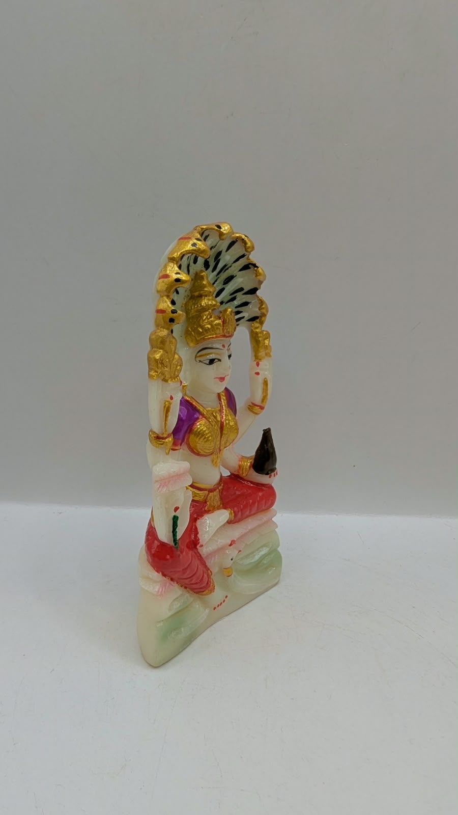 White Padmavati Devi statue with peacock arch, side view