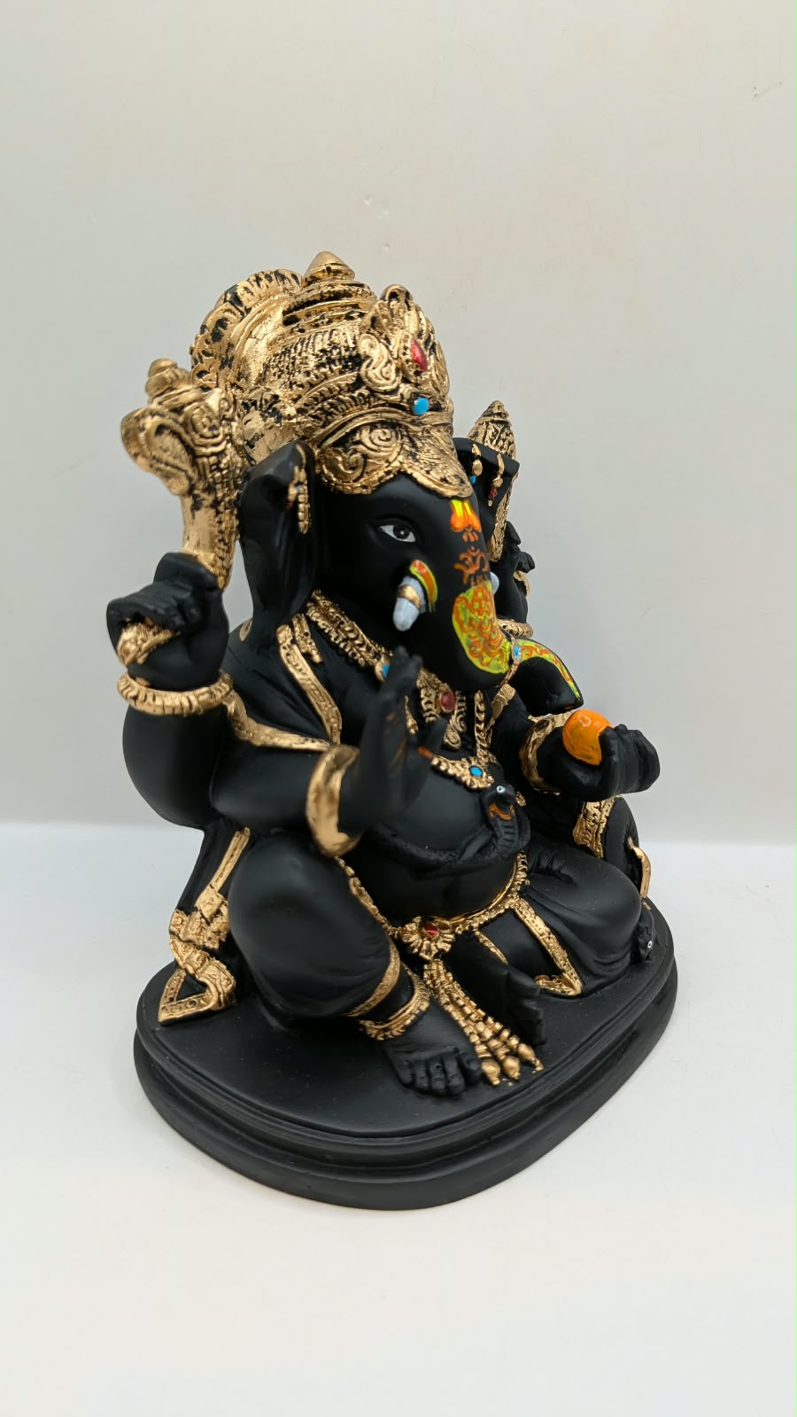 Black and gold Ganesh statue with crown, side view