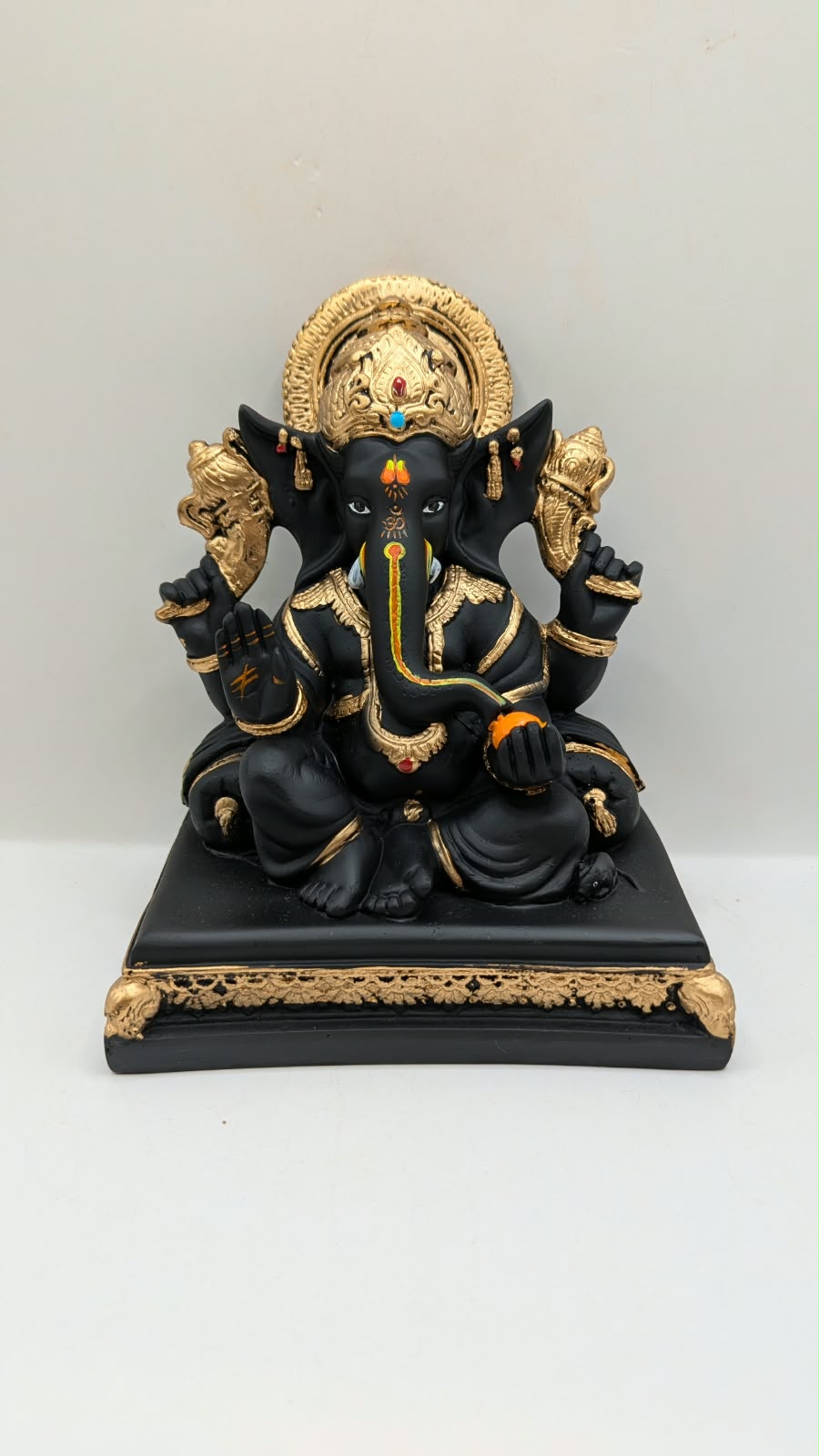 Black and gold Ganesh statue on throne base, front view