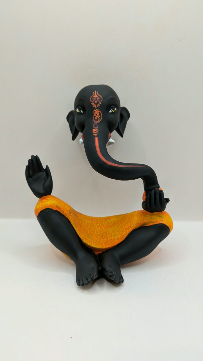 Modern black Ganesh statue with orange dhoti, front view