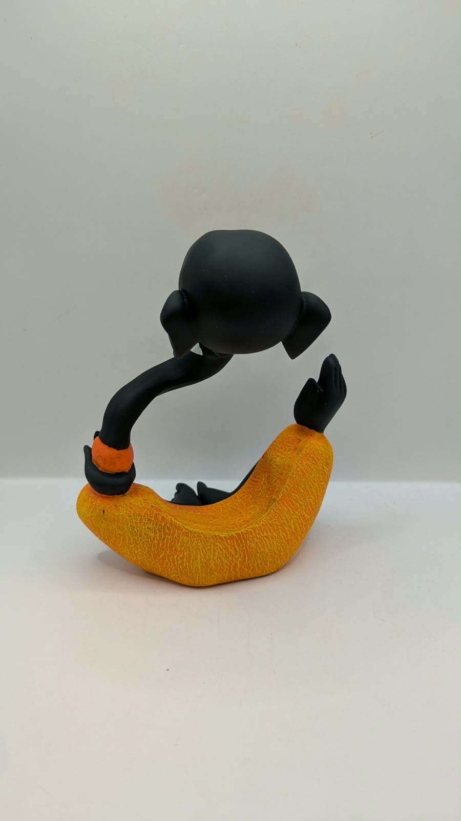 Modern black Ganesh statue with orange dhoti, back view