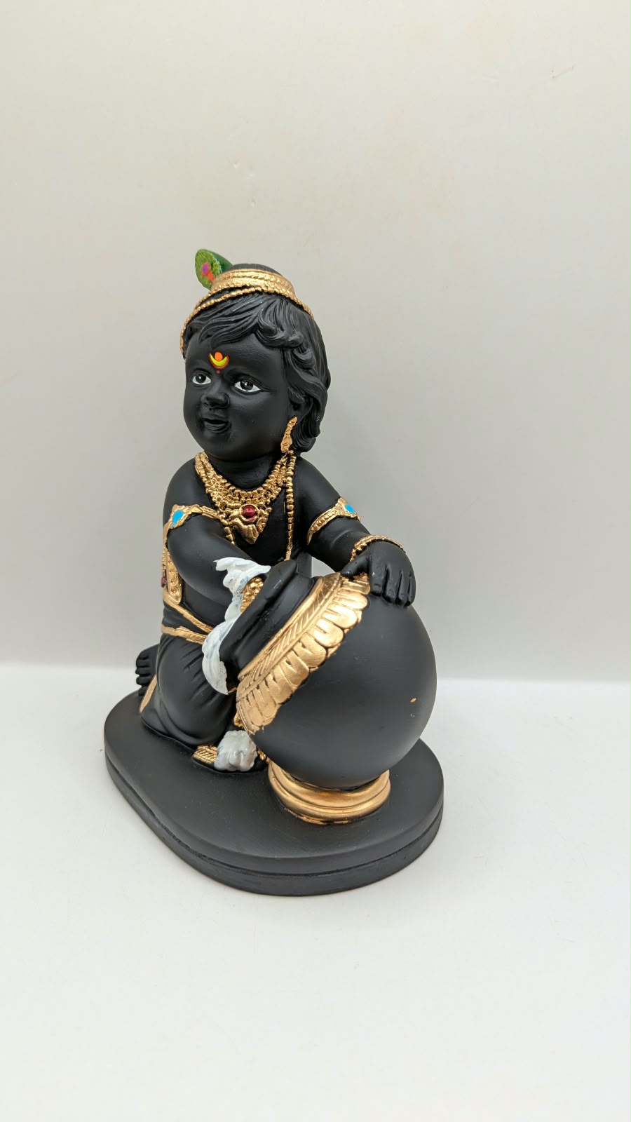Black and gold baby Krishna statue with butter pot, other side view
