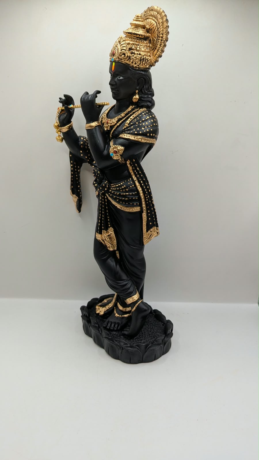 Tall black and gold Krishna statue on lotus base, other side view