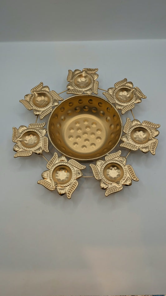 Gold metal urli bowl with 7 lotus diyas, top view