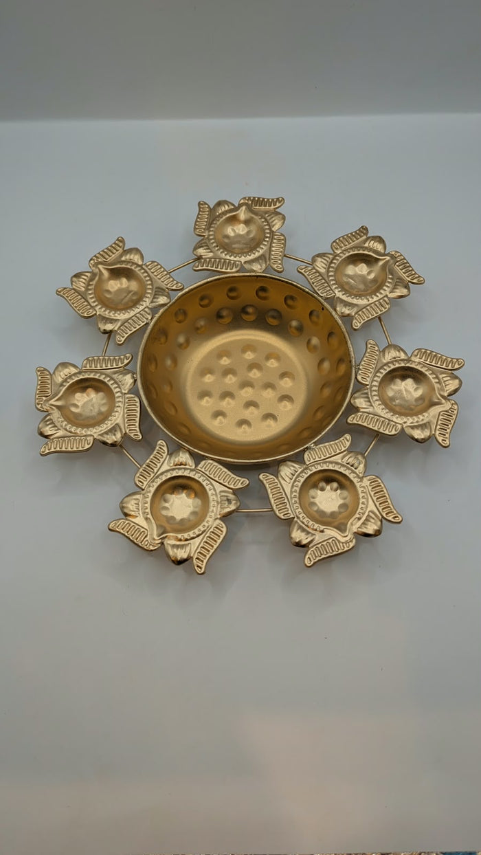 Gold metal urli bowl with 7 lotus diyas, top view