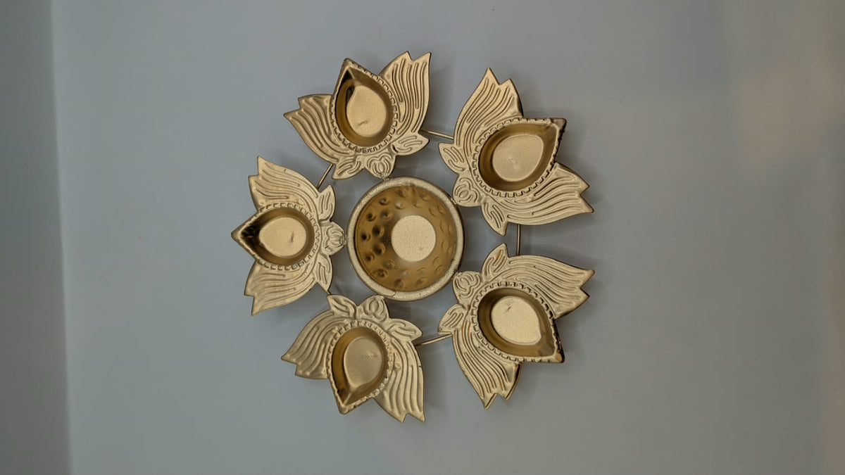 Gold metal urli bowl with 5 petal diyas, top view