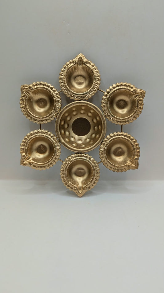 Gold metal urli bowl with 6 round diyas, front view