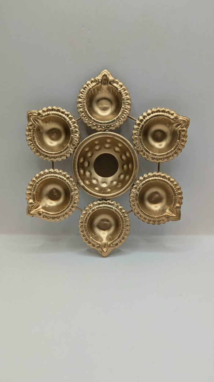 Gold metal urli bowl with 6 round diyas, front view