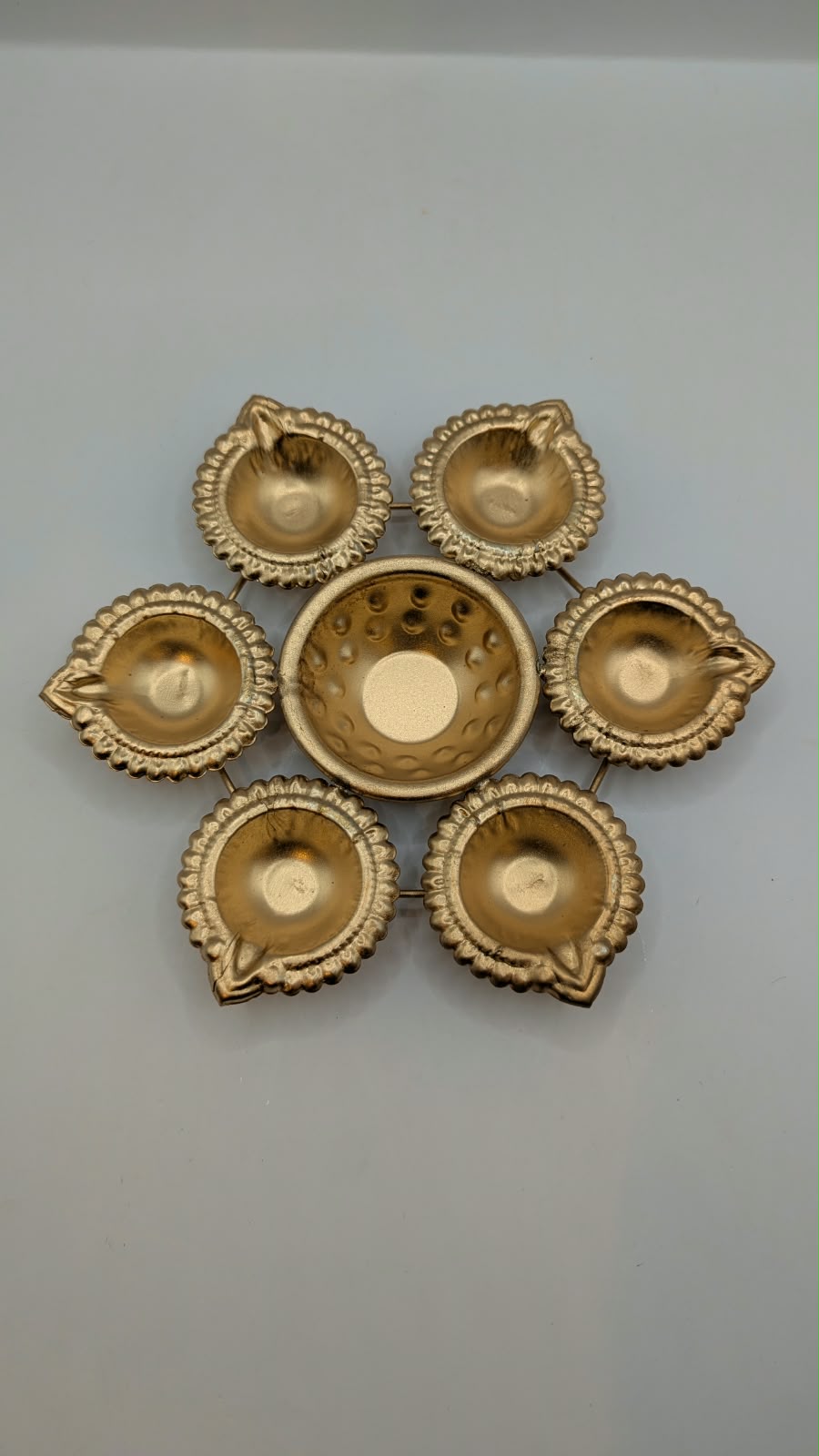 Gold metal urli bowl with 6 round diyas, top view