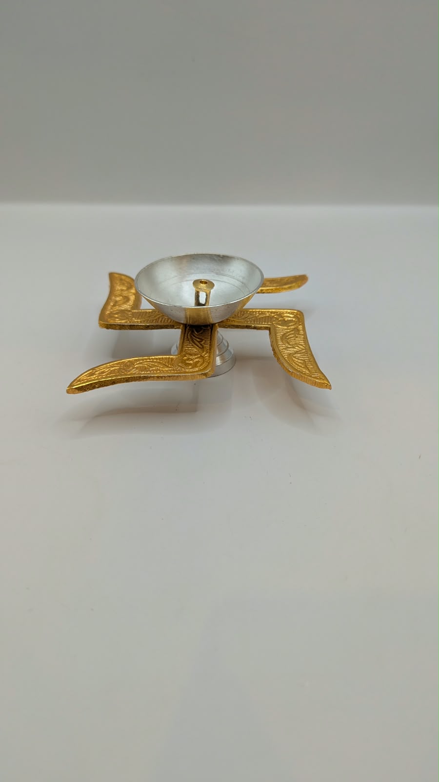 Gold and silver swastik diya, side view