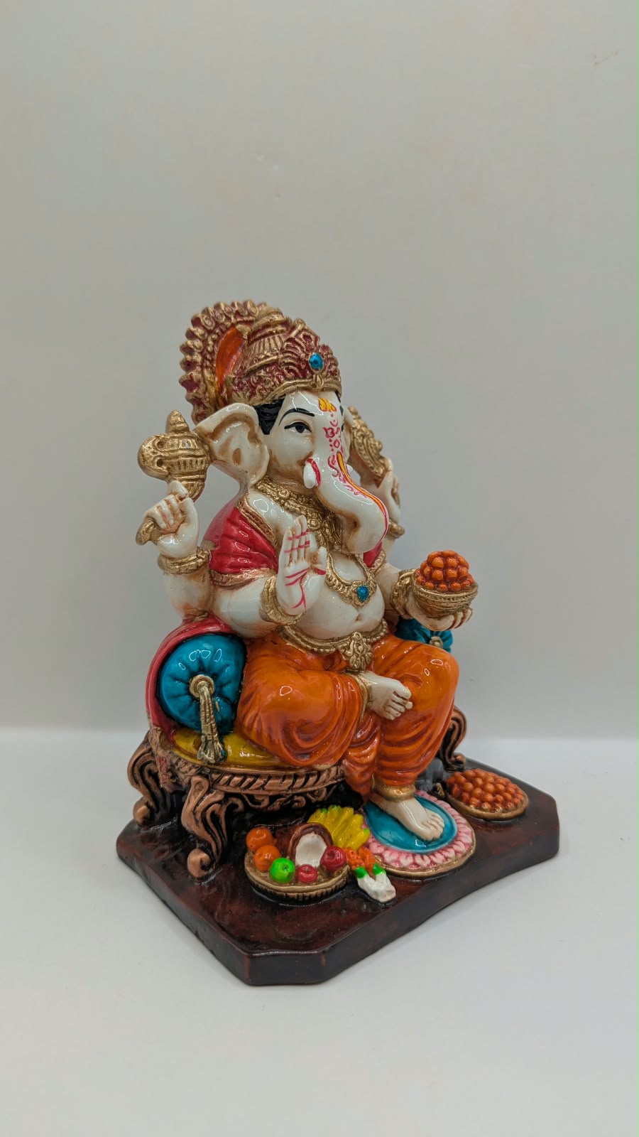 Orange and gold Ganesh statue on throne, side view
