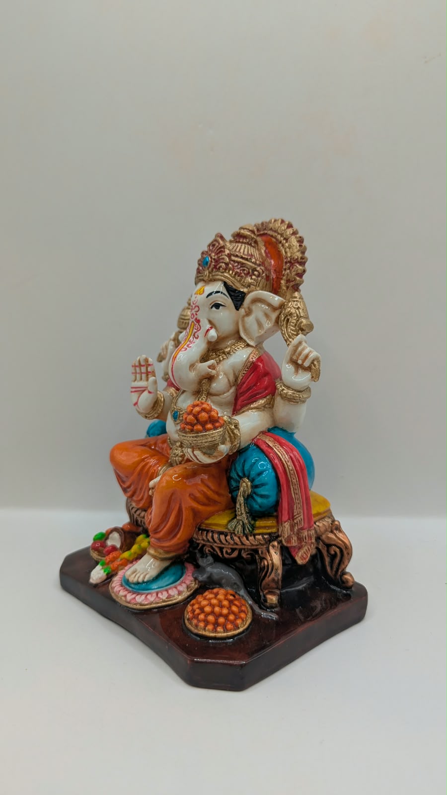 Orange and gold Ganesh statue on throne, other side view
