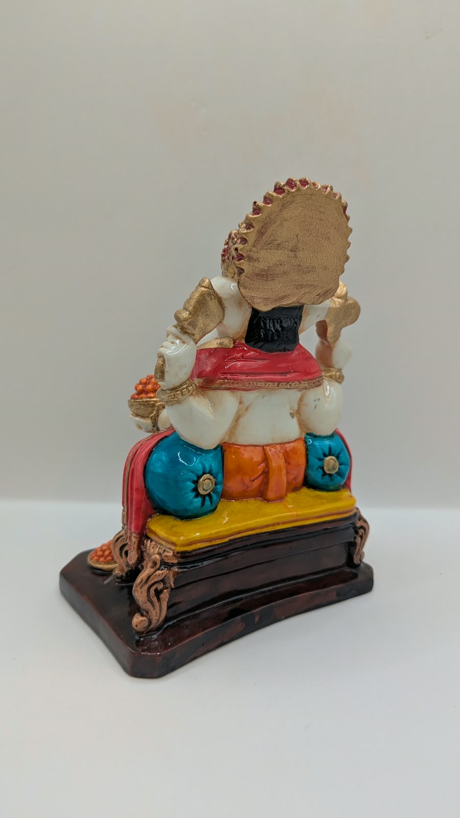 Orange and gold Ganesh statue on throne, back view