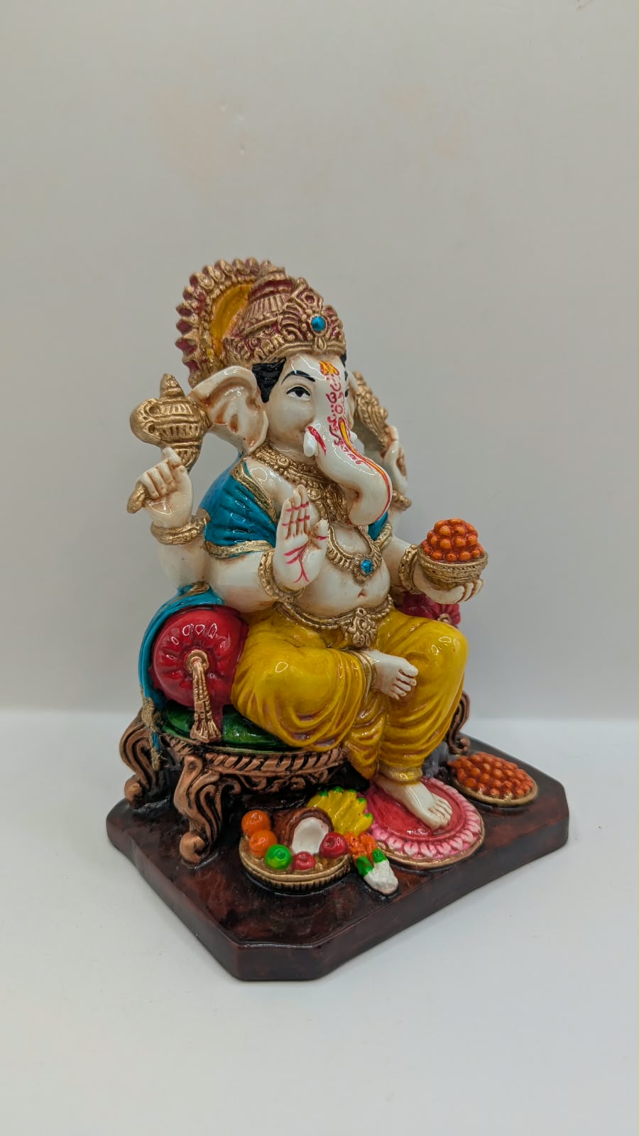 Yellow and gold Ganesh statue on throne, side view