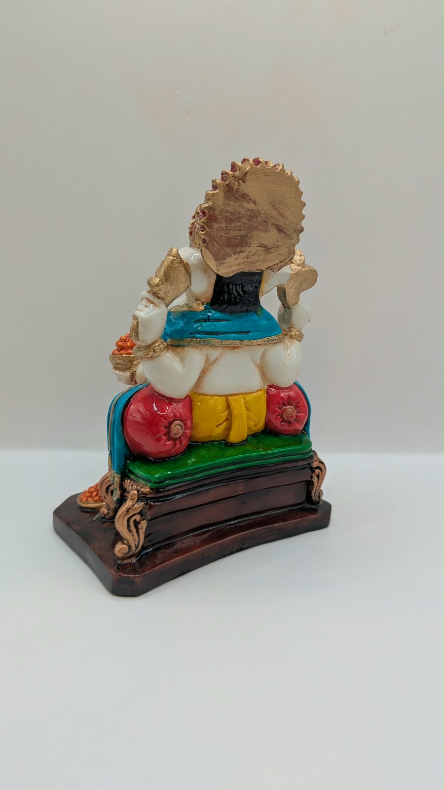 Yellow and gold Ganesh statue on throne, back view