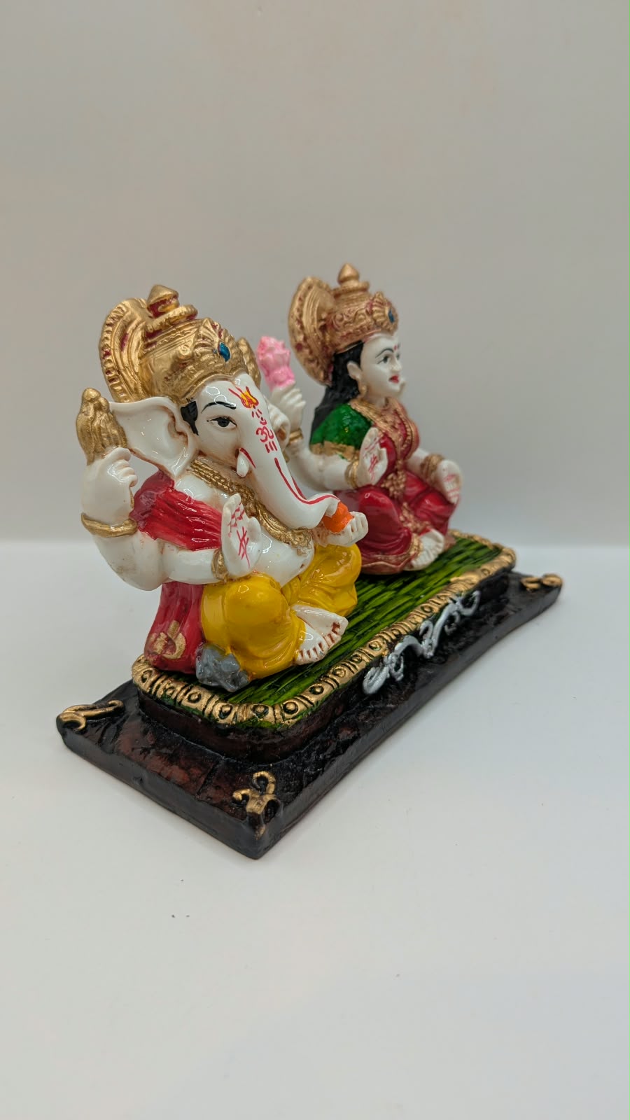 Ganesh and Laxmi statue on green mat, side view