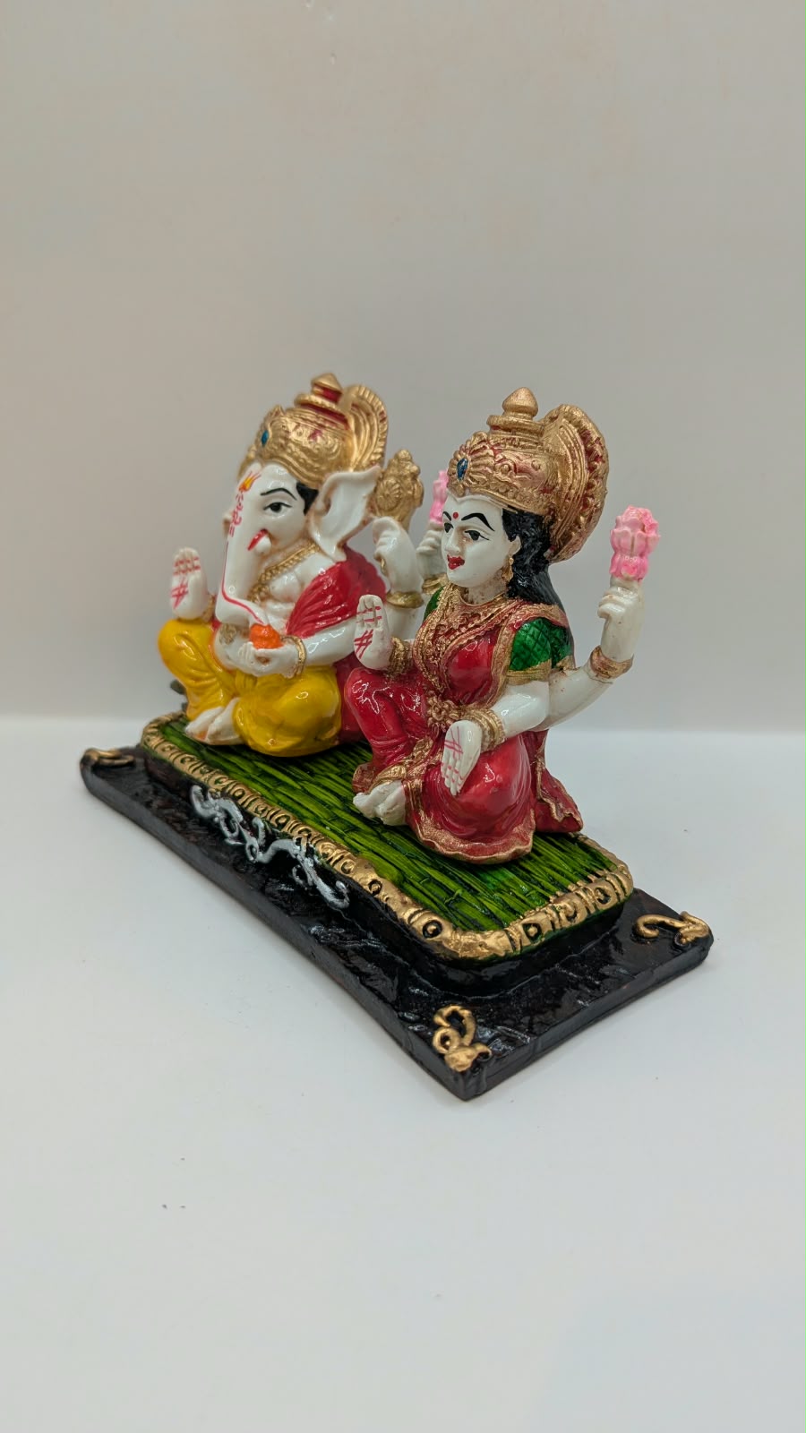 Ganesh and Laxmi statue on green mat, other side view
