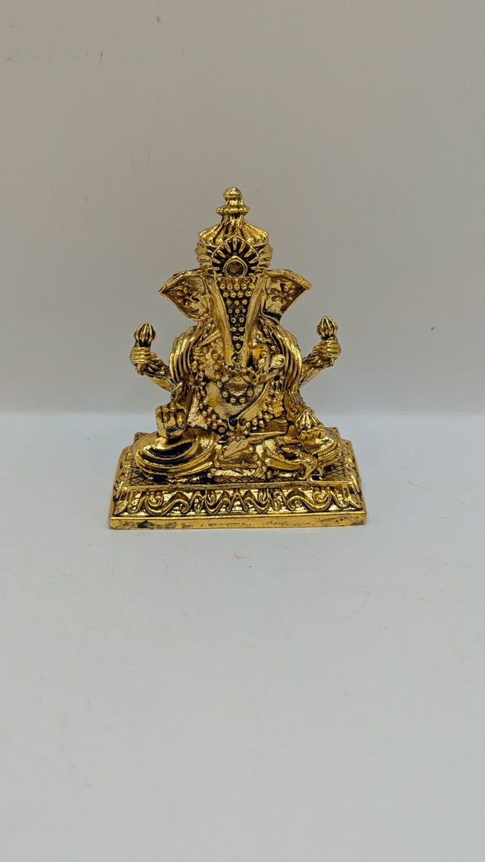 Gold Ganesh murti on square base, front view