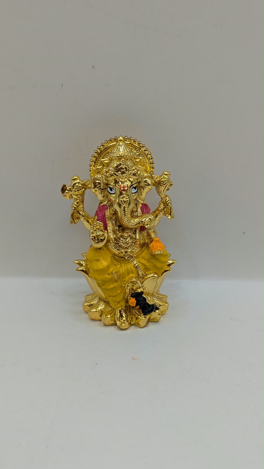 Gold Ganesh murti on lotus, front view