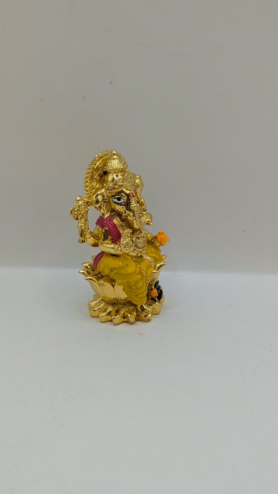 Gold Ganesh murti on lotus, side view