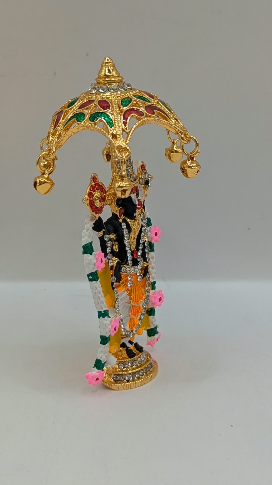 Gold Tirupati Balaji murti under umbrella, side view