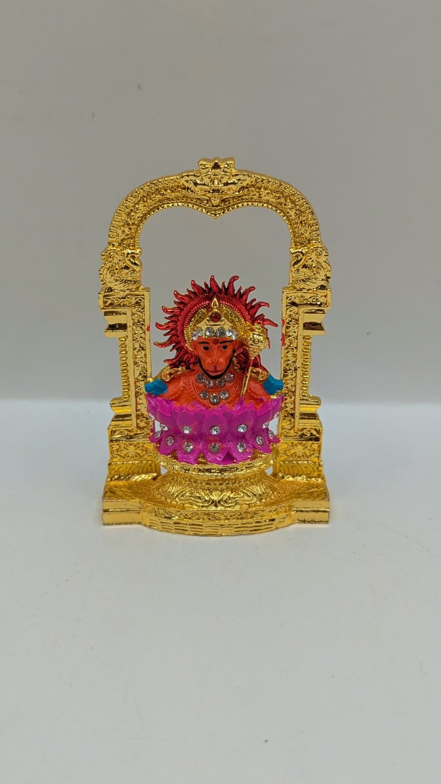 Gold Ganesh murti in temple arch on pink lotus, front view