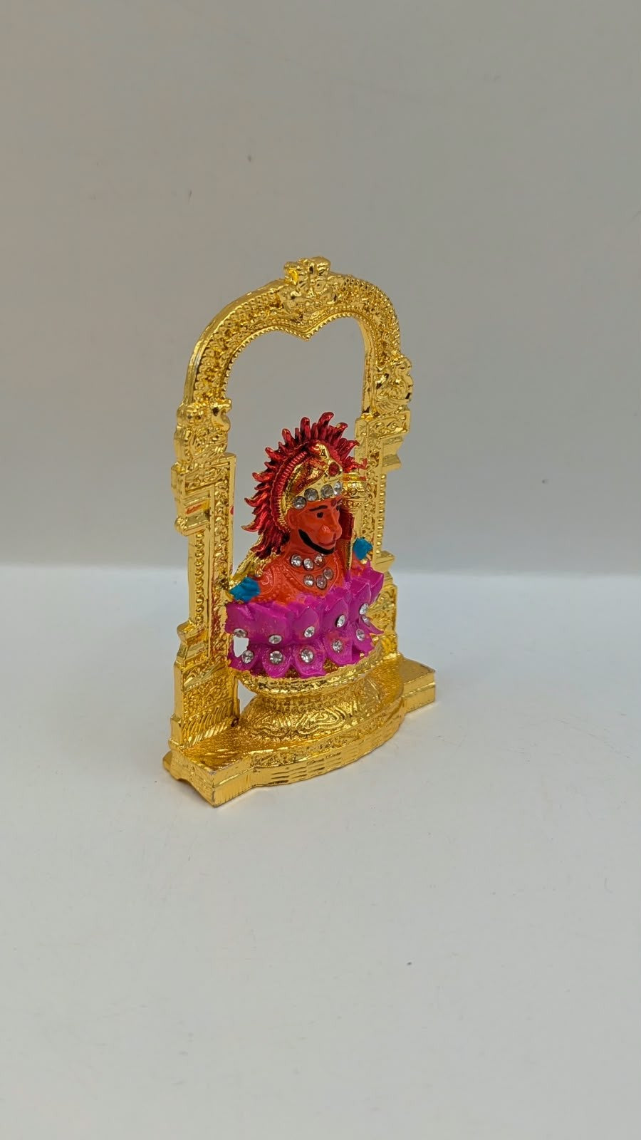 Gold Ganesh murti in temple arch on pink lotus, side view