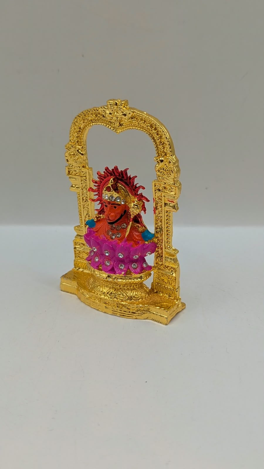 Gold Ganesh murti in temple arch on pink lotus, other side view