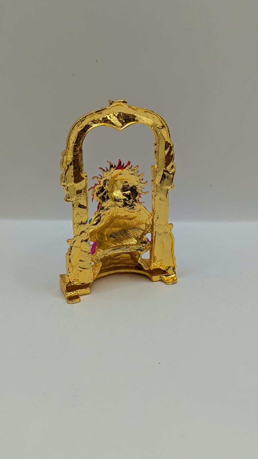 Gold Ganesh murti in temple arch on pink lotus, back view