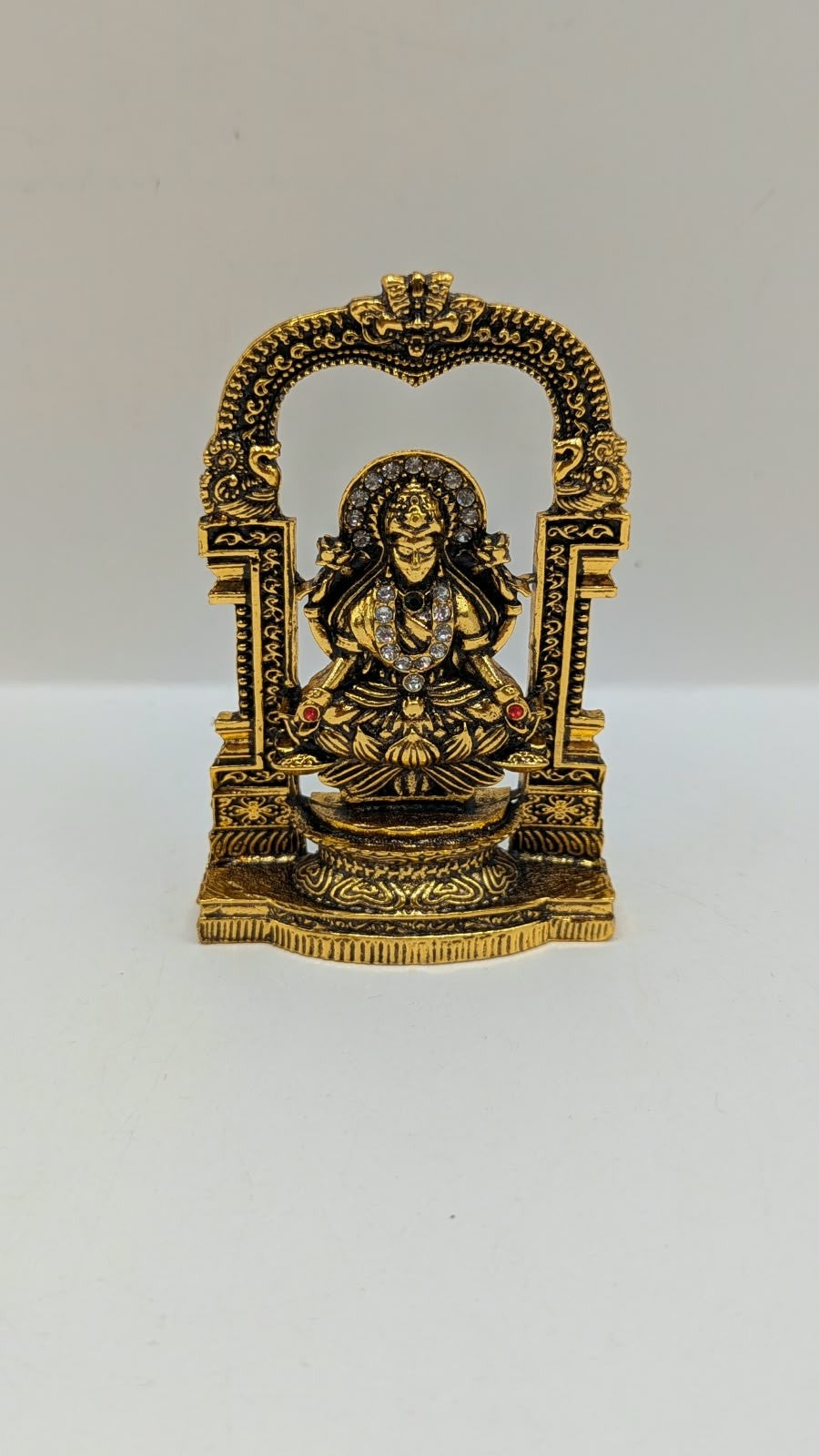 Antique gold Laxmi murti in temple arch, front view