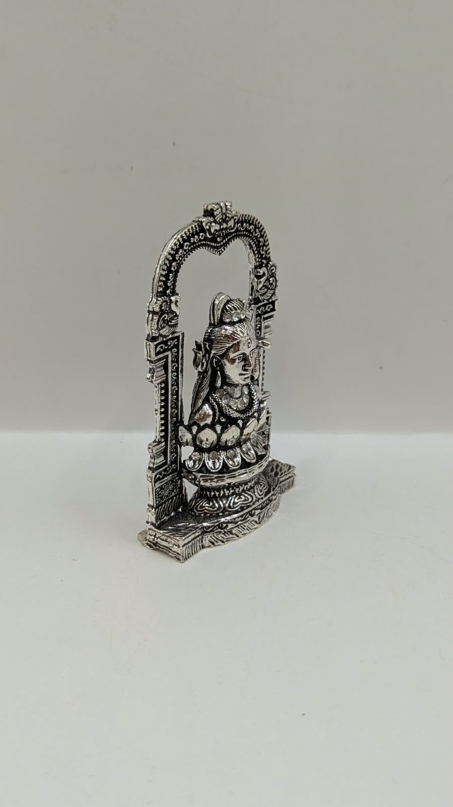 Silver Shiva murti in temple arch on lotus, side view