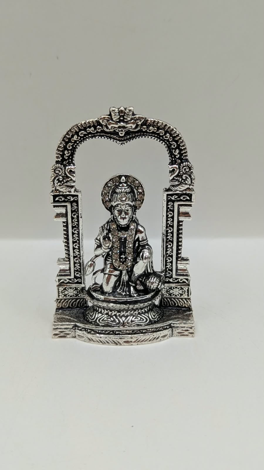 Silver Hanuman murti in temple arch, front view