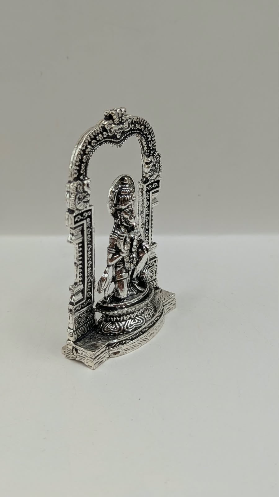 Silver Hanuman murti in temple arch, side view