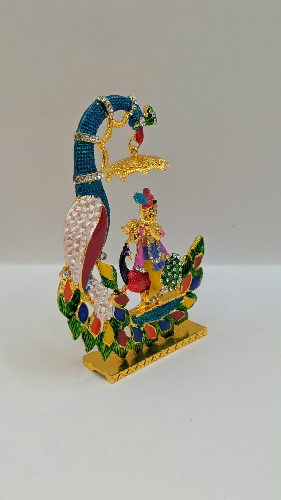 Colourful Krishna with peacock and umbrella murti, side view